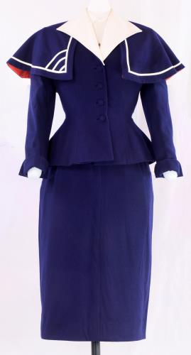 Front view of a navy wool skirt and jacket over a sheer, synthetic button-down blouse from the 1940s