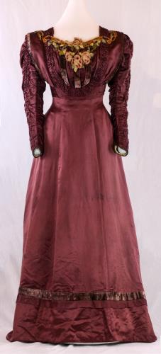 Front view of a long maroon satin empire gown from the 1910s