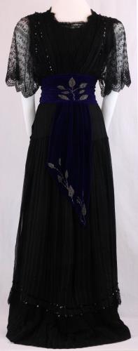 Back view of a one piece, black dress with short train, circa 1910.