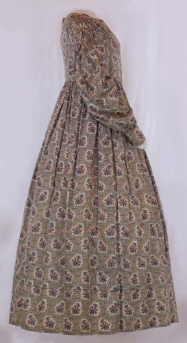 Side view of a long sleeved flower print pioneer ladies dress from the 1830s